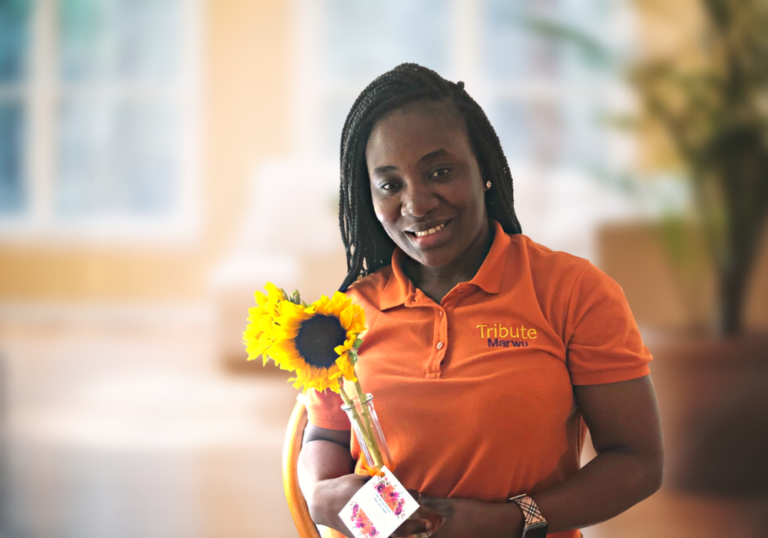 Tribute Caregiver Marwu smiles with flowers from Tribute Home Care