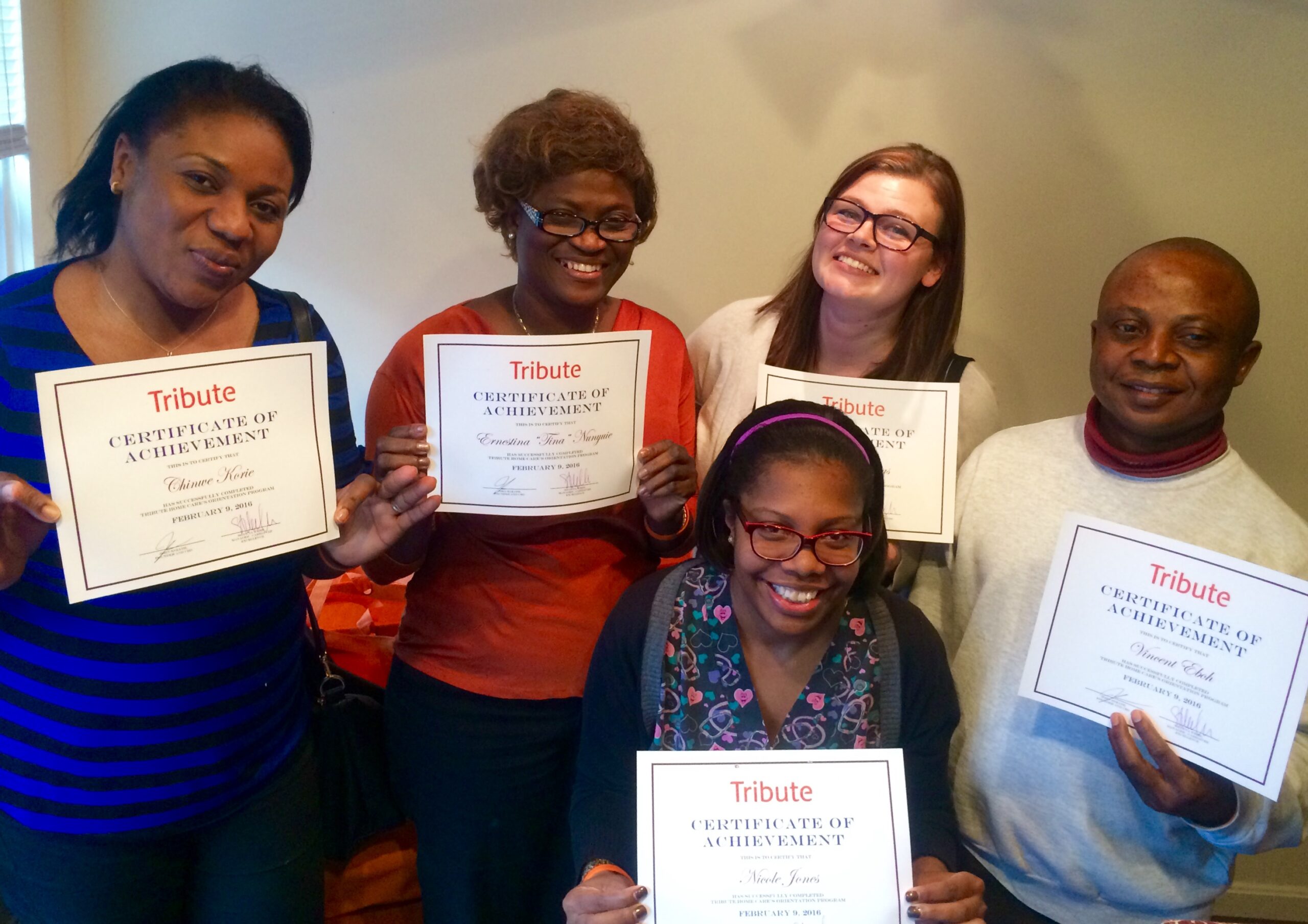 5 Tribute Caregivers smile and celebrate together holding certificates of achievement for completing orientation