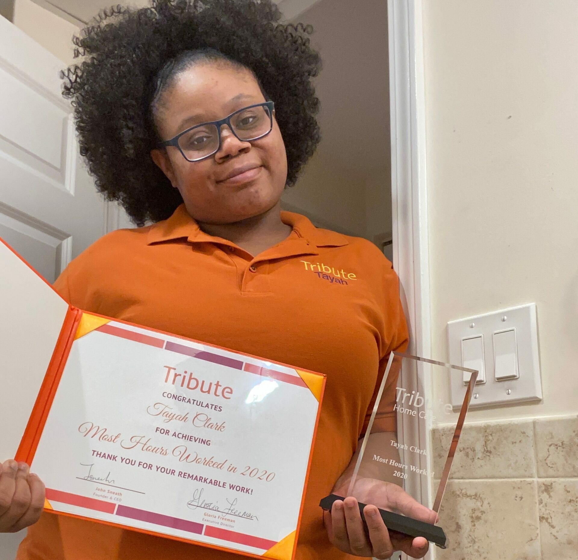 Tribute Caregiver Tayah smiling and holding certificate 