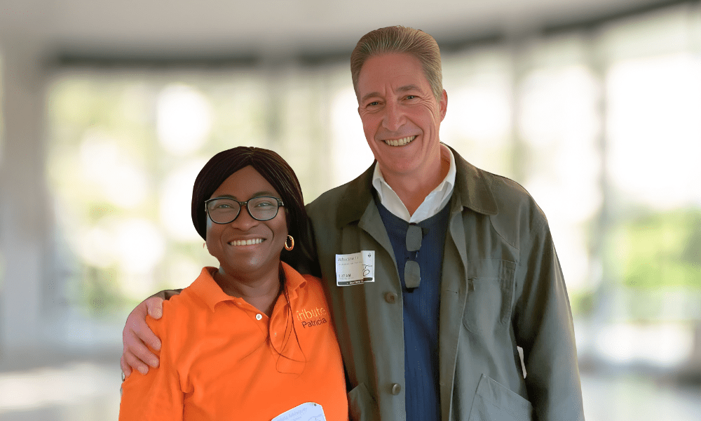 Tribute Caregiver Patricia smiling in Tribute Home Care uniform next to John Sneath, Founder and CEO