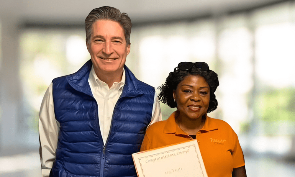 Tribute Caregiver smiling in Tribute Home Care uniform with Certificate next to John Sneath, Founder and CEO