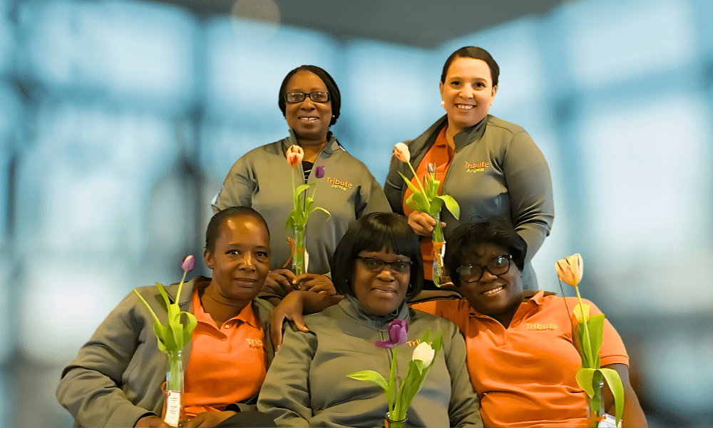 5 Tribute Caregivers smiling in Tribute Home Care uniforms holding flowers