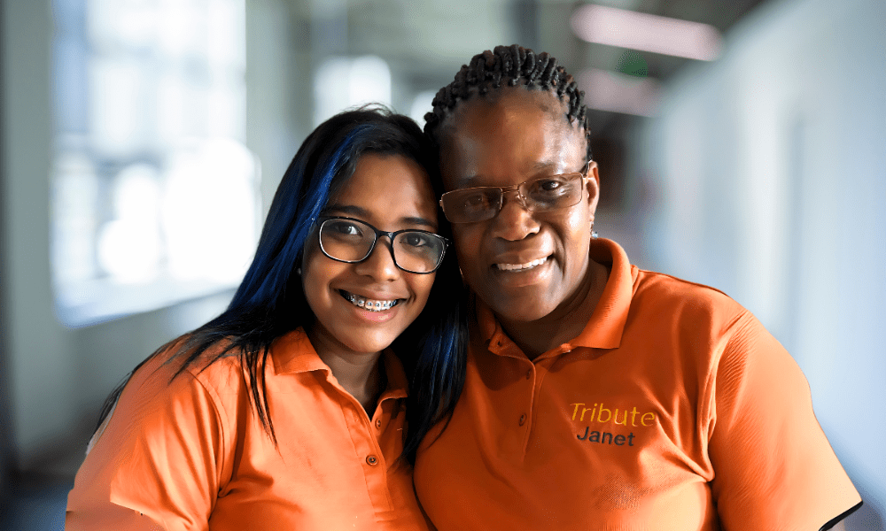 2 Tribute Caregivers smiling in Tribute Home Care uniforms