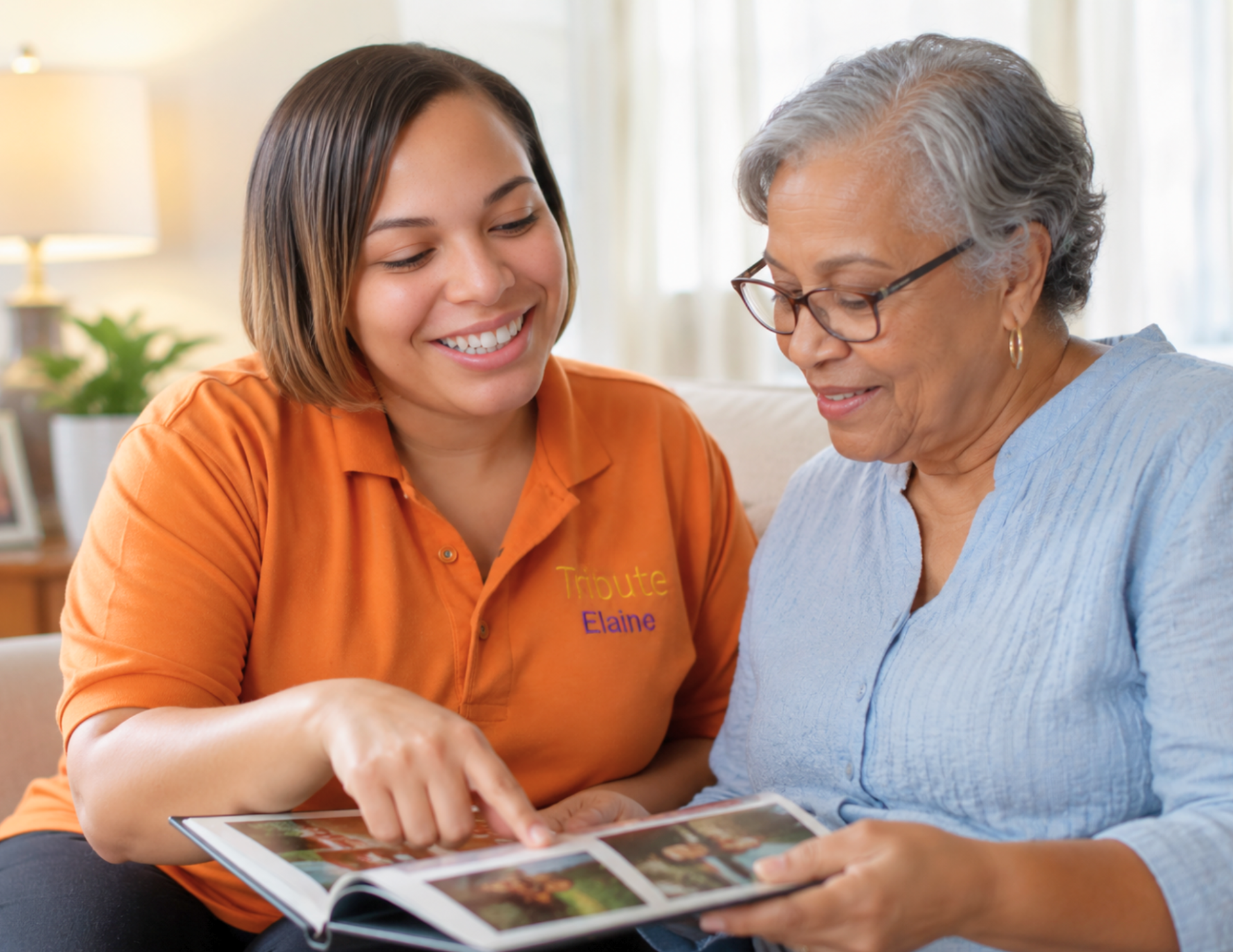Tribute Home Care Caregiver sitting with an older adult at home looking through a photo album together.